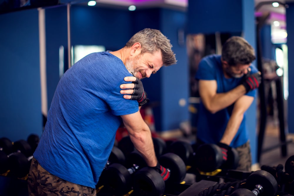 man with shoulder pain training with dumbbells